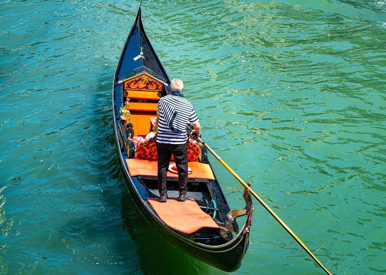 A man driving a Godola in Venice on a sunny day